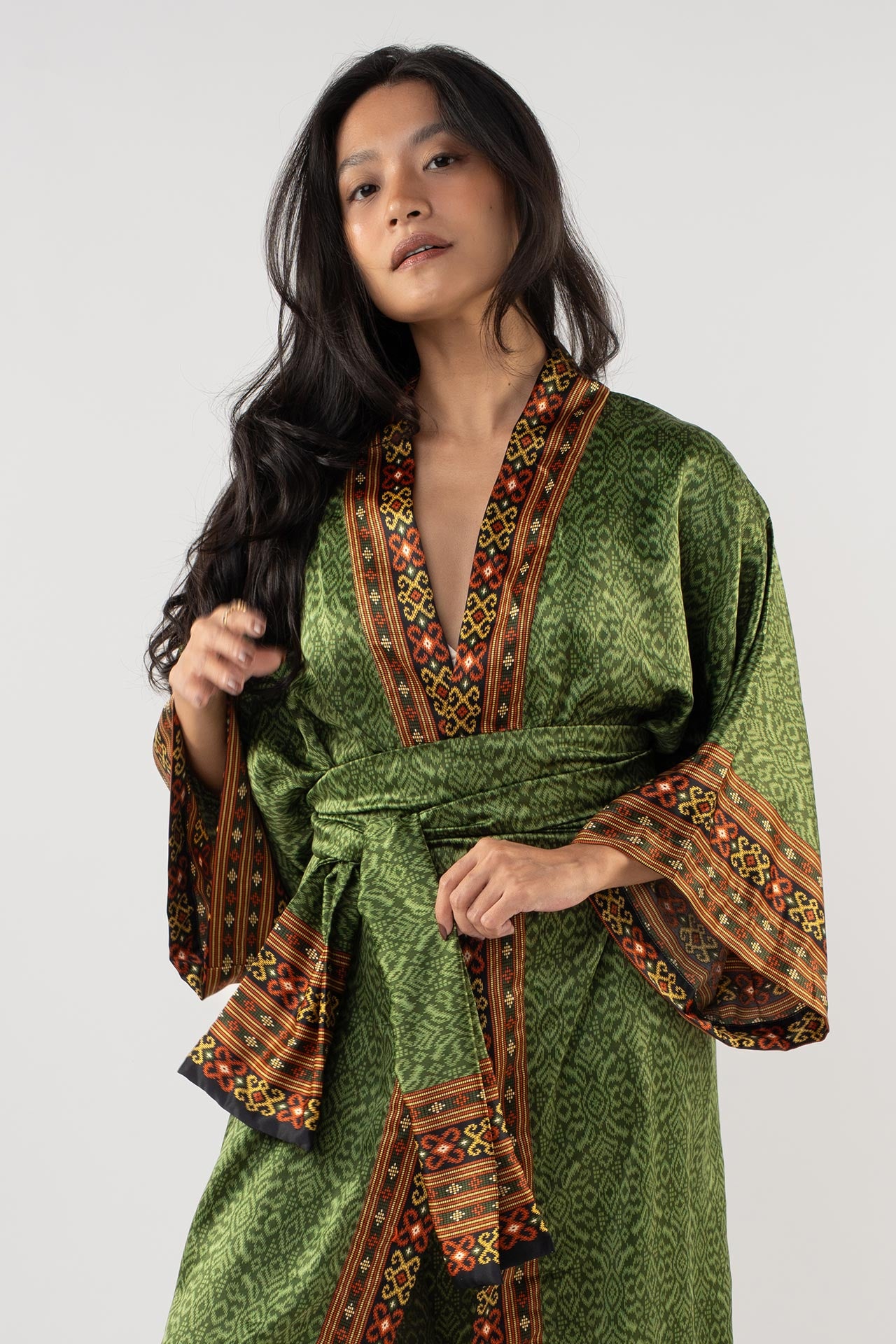 Woman wearing a green dress with intricate patterns on a white background