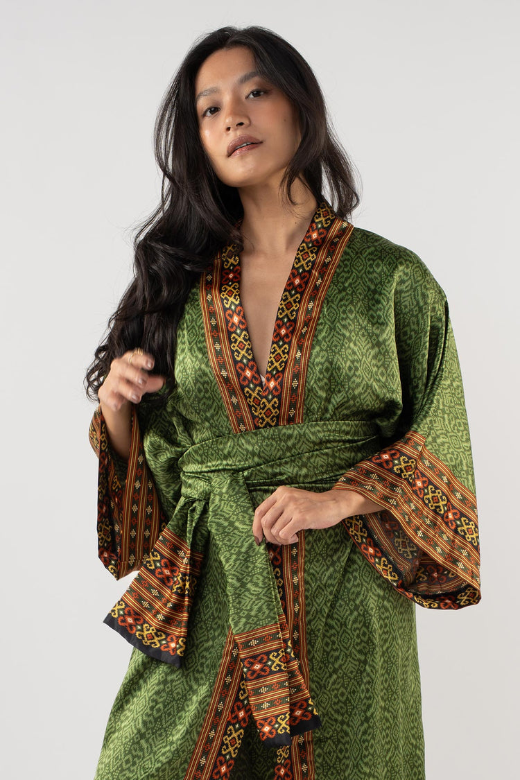 Woman wearing a green dress with intricate patterns on a white background